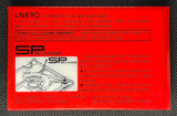 The back of the wrapper of a vintage Sony 1978 LNX 90 cassette tape and its original red-and-black plastic case, displayed on a dark textured surface.